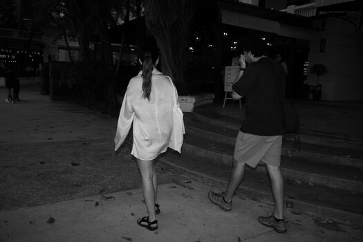 Two people jogging at night on a city street in black and white.