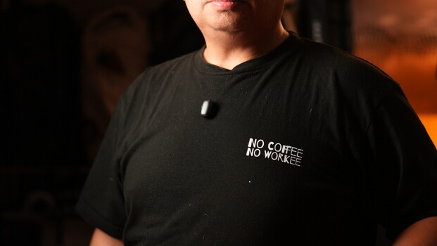 Person wearing black t-shirt with "NO COFFEE NO WORKEE" text printed on chest.