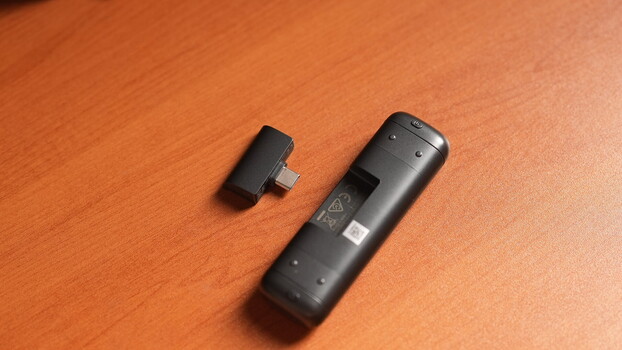 Two black wireless remote controls displayed on an orange wooden surface.