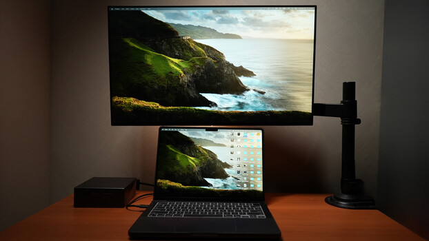 Dual-monitor setup with laptop displaying coastal landscape photography on both screens.