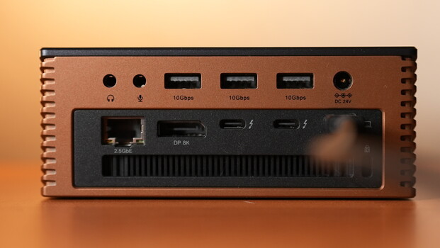 Desktop interface device with copper heatsink cooling fins, displaying multiple USB ports and network connections on black panel.