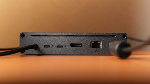 Dark gray networking device with USB ports, Ethernet jack, and cable connections against warm orange background.