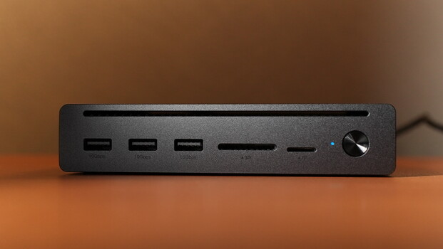 Black rectangular desktop device with three USB ports, SD card slot, and volume control knob on warm wooden surface.