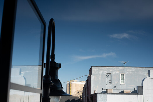 View from inside a vehicle looking through the windshield at urban buildings and clear sky.