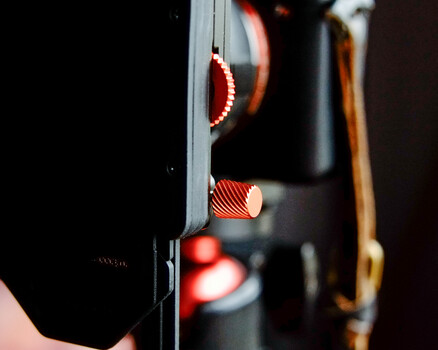 Close-up of glowing red LED lights on camera equipment against dark background.