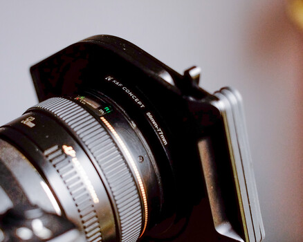 Vintage rangefinder camera with attached lens, shot in close-up against a blurred background.
