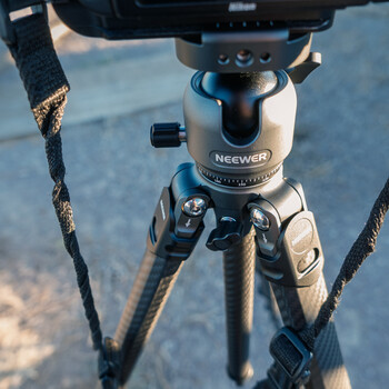 Neewer tripod head with ball mount and three rope-stabilized legs against blue water background.