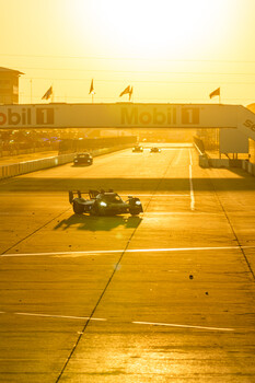 Parked motorcycle on an empty airport tarmac bathed in golden sunset light.