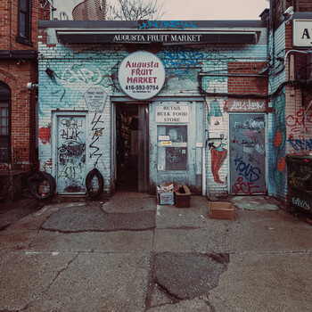 Weathered storefront with turquoise painted brick facade and graffiti tags.