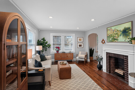 Residential living room with hardwood floors, fireplace, and warm wood furnishings arranged for comfortable seating.