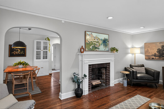 Bright residential living room with fireplace, wood floors, and mixed period furnishings.