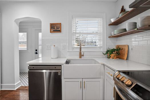 Modern kitchen with white cabinetry, stainless steel appliances, and natural light from window above sink.