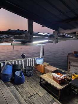 Lakeside dock setup at twilight with camera equipment and tools arranged on wooden platform.