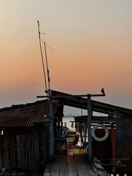 Silhouetted wooden structures with antennas against a warm sunset sky.