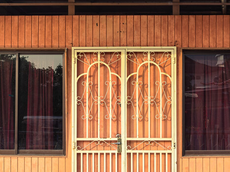 Ornate arched double doors with decorative ironwork on a warm-toned wooden storefront.