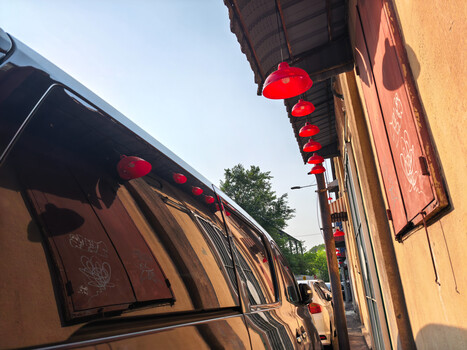 Red fabric lanterns hanging from traditional yellow-ochre building eaves along a narrow street.