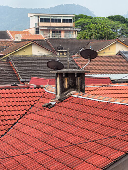 Aerial view of residential rooftops with red clay tiles and a chimney structure in foreground.