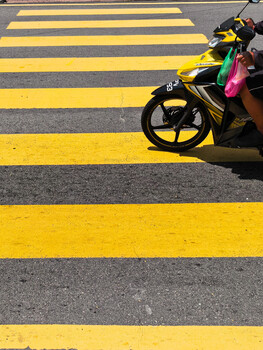 Yellow and black striped crosswalk with a yellow motorcycle parked at the edge.