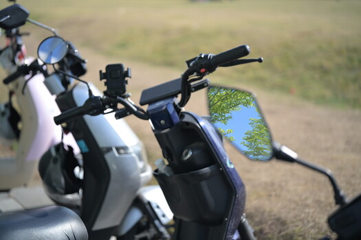 Close-up of two scooters parked outdoors with a smartphone displaying a map in the foreground.