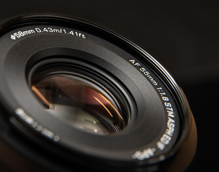 Close-up of a camera lens barrel showing focal length markings and aperture specifications against a dark background.