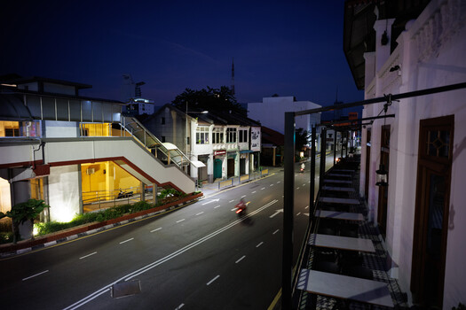 Nighttime urban street scene with modern and traditional architecture, warm ambient lighting, and empty roadway.