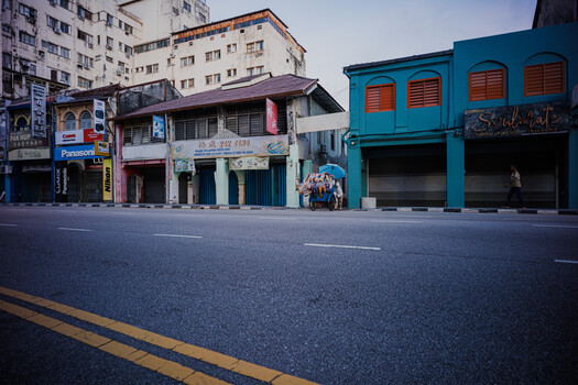 Street-level view of colorful storefronts with shuttered shops and residential apartments above.