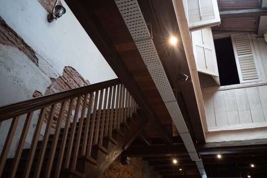 Wooden staircase shot from below with dramatic upward perspective, warm interior lighting, and architectural framing.