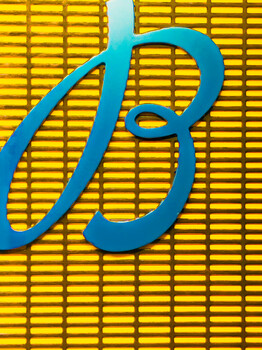 Blue stylized letter B against a yellow corrugated or ridged background pattern.