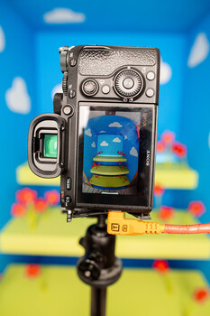 Vintage film camera mounted on tripod with colorful blurred background.