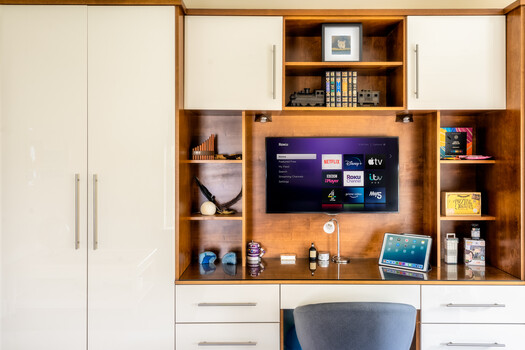 Built-in shelving unit with organized workspace featuring TV display and storage