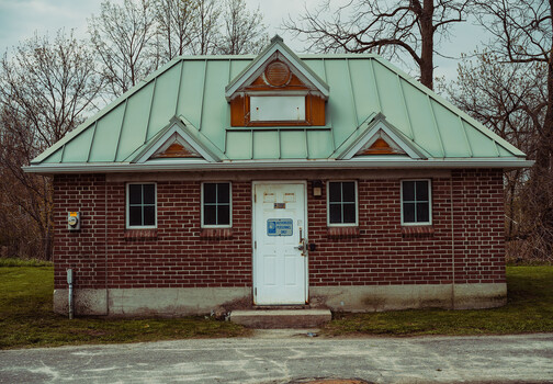 Red brick building with green metal roof and white entrance door
