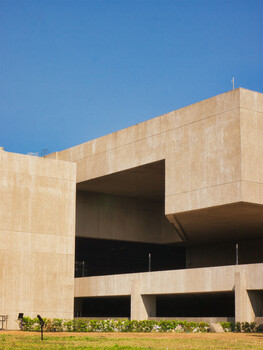 Modern brutalist architecture with cantilevered concrete volumes against clear blue sky