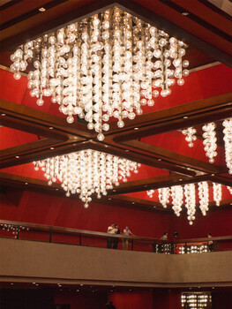 Elaborate crystal chandelier installations suspended from red ceiling with wooden beams