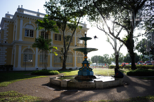 Colonial-style yellow building with ornate fountain and manicured grounds