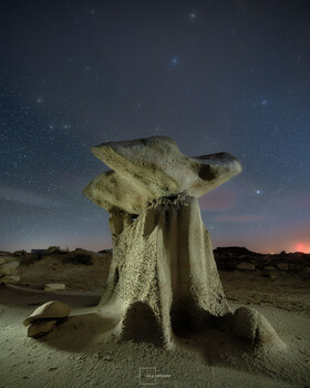 Illuminated rock formation against starry night sky in desert landscape