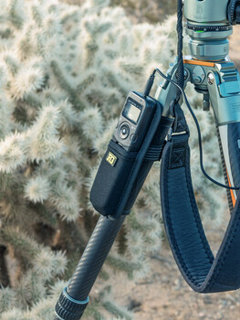 Camera gear hanging from shoulder strap against patterned textile background