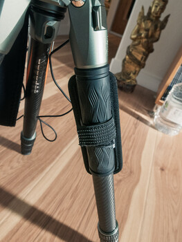 Microphone with windscreen on wooden surface surrounded by audio recording equipment