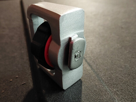 Tape dispenser with red and black tape roll mounted on white foam housing with metal latch