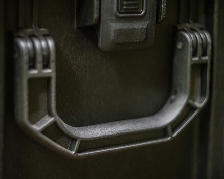 Close-up of metal carrying handle on tactical gear case with weathered finish