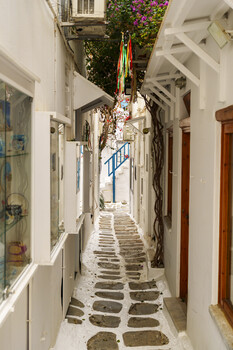 Narrow whitewashed alleyway with stone steps descending between Mediterranean-style buildings