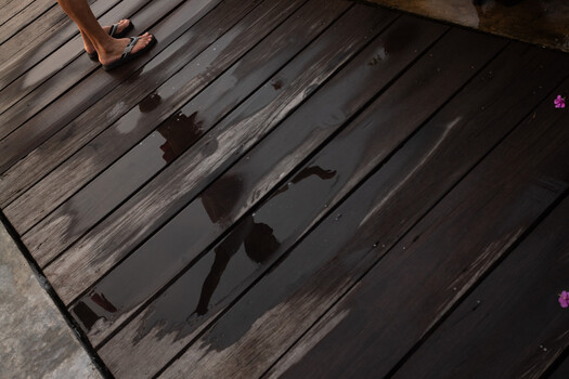 Shadow of a person in motion cast on wet wooden deck planks