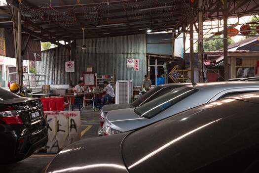 Auto repair garage with parked cars and workers visible through corrugated metal storefront