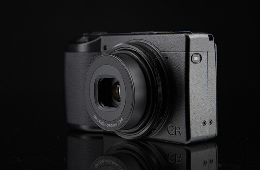 Ricoh GR compact digital camera against black background with reflection