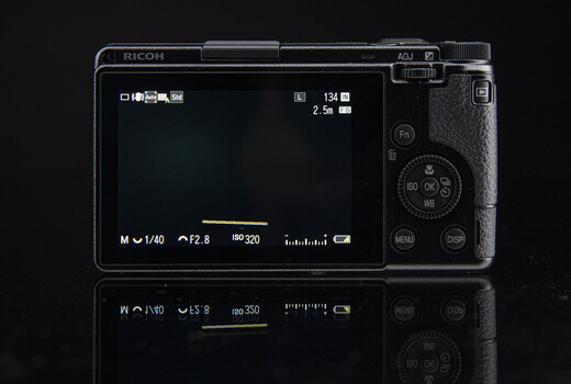 Ricoh compact camera rear LCD screen displaying exposure settings and menu interface