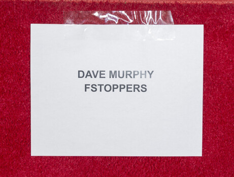 White card or label with "DAVE MURPHY" and "FSTOPPERS" text on red textured background