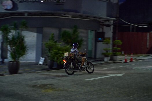 Motorcycle rider in motion on urban street at night with motion blur