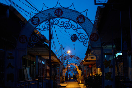 Twilight street scene with decorative blue archway and warm golden storefronts