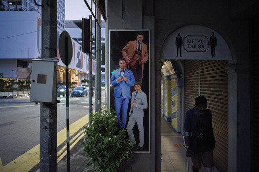 Street photography of storefront display with tailored suit mannequins at night