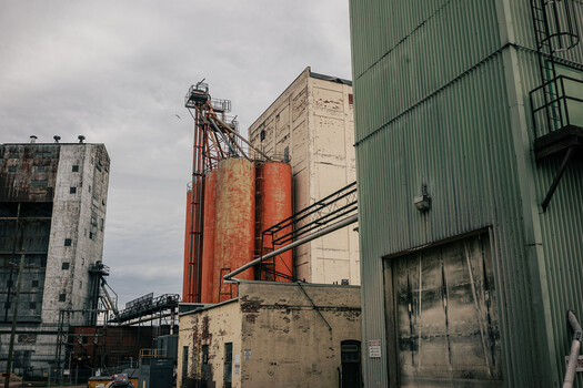 Industrial grain silos and corrugated metal warehouses under overcast sky