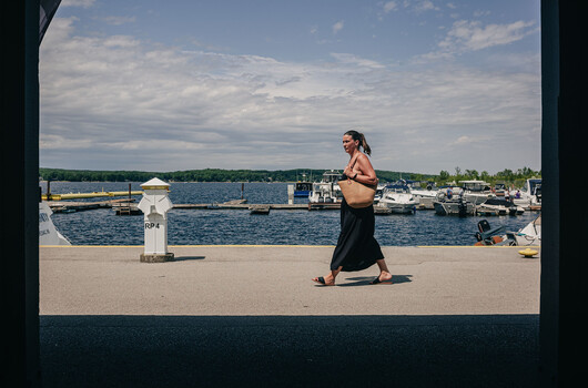 Woman jogging on waterfront promenade with marina and boats in background